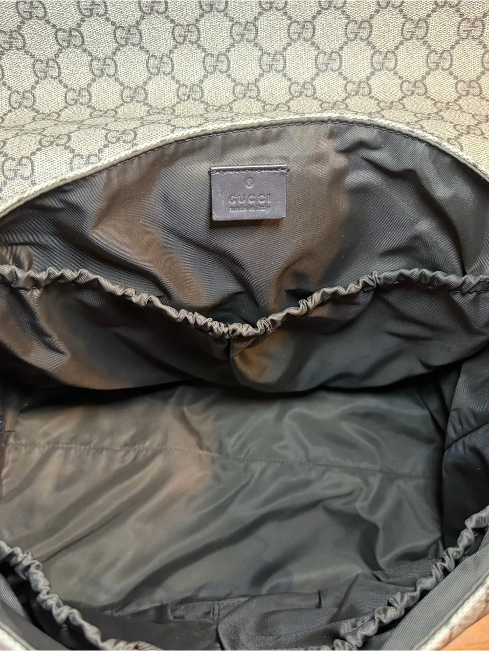 GG Supreme canvas diaper bag, designed with multiple pockets and fold-out pad
